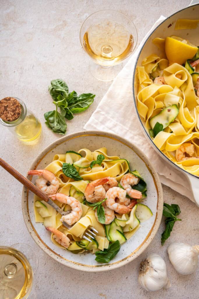 pappardelle with zucchini and shrimp in a bowl with a spoon.