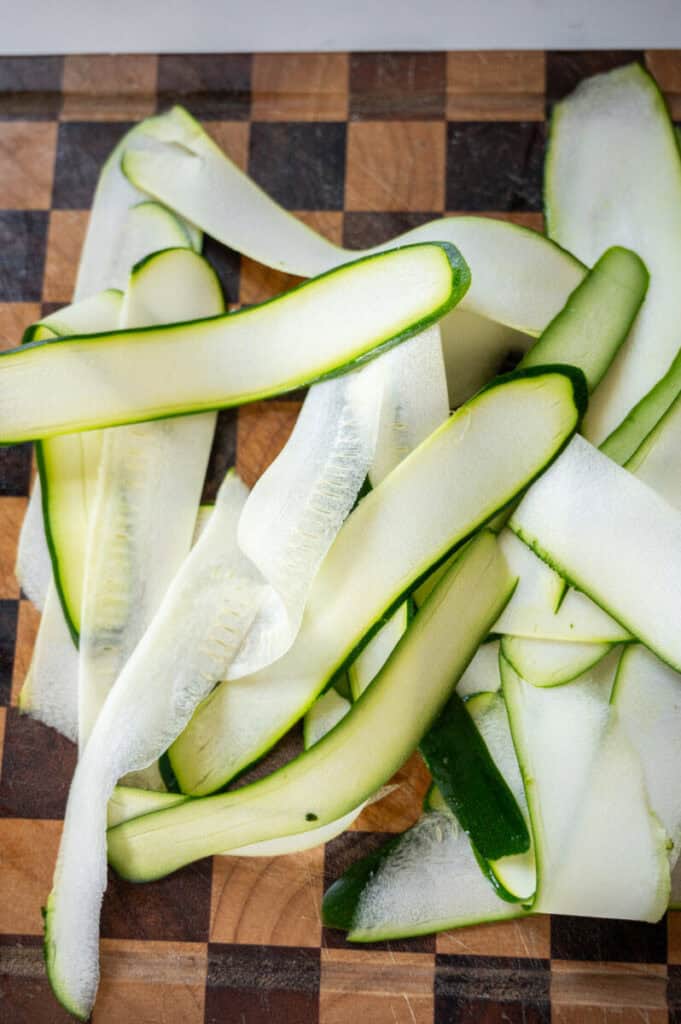 thinly sliced zucchini on a cutting board.