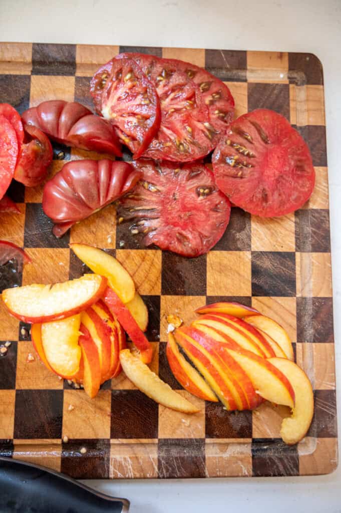 peaches and tomatoes on a cutting board.