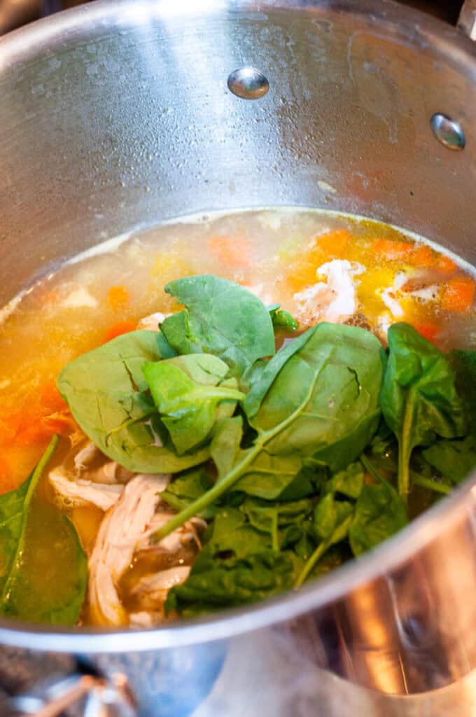 chicken and spinach in soup pot.