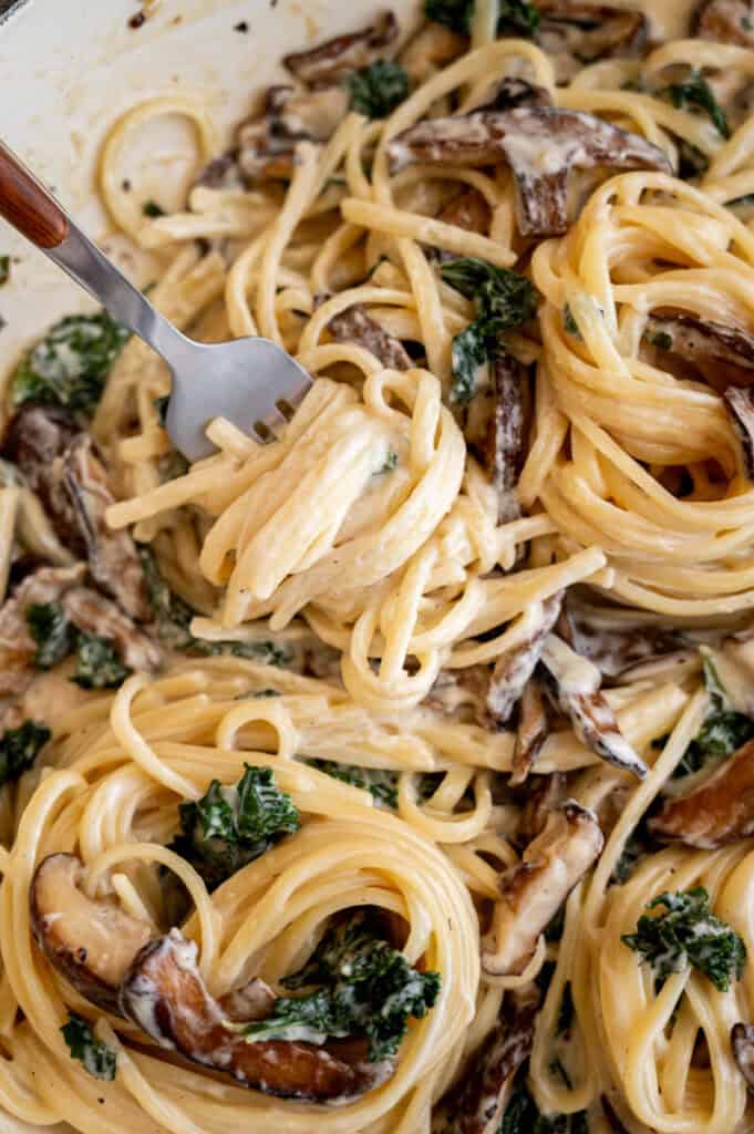 creamy mushroom and kale pasta twirled on a fork.