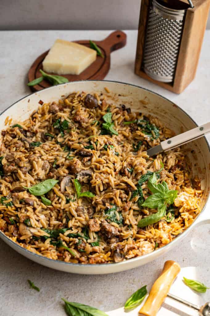 one pot sausage and spinach orzo with a spoon.