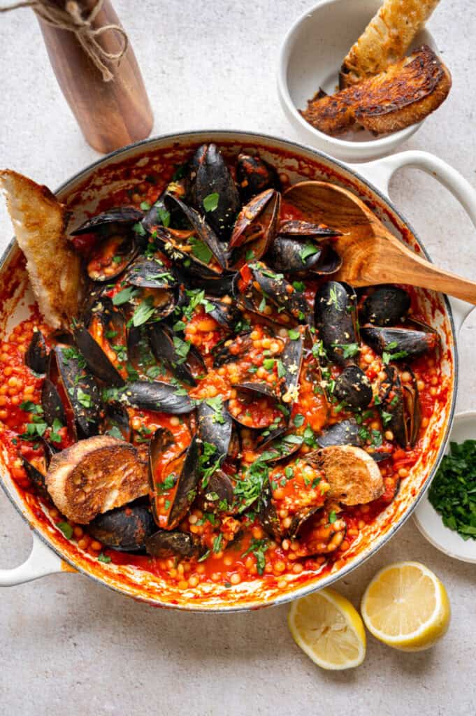 mussels with Israeli couscous in a skillet.