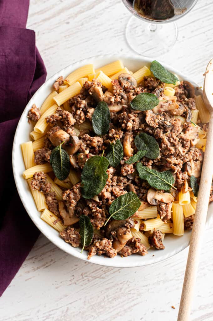 Sausage and Mushroom Rigatoni with Crispy Sage in a bowl with a serving spoon