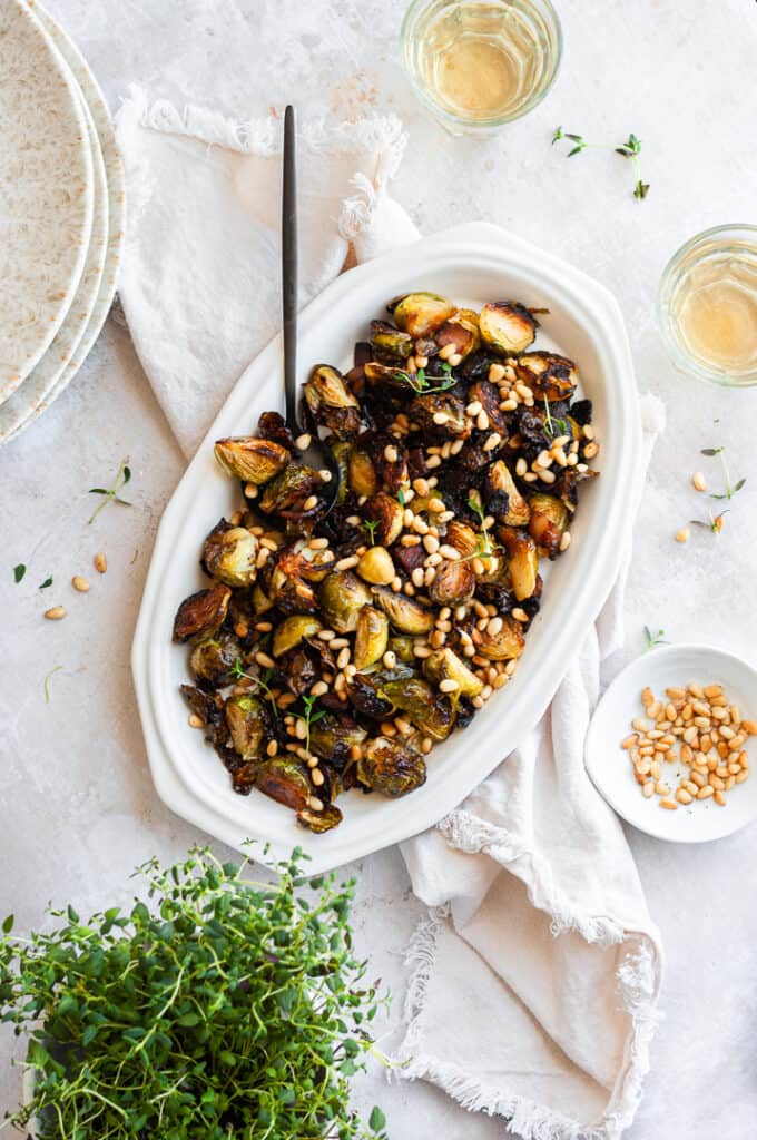 Maple Bacon Brussels sprouts with glasses of wine, pine nuts, and thyme