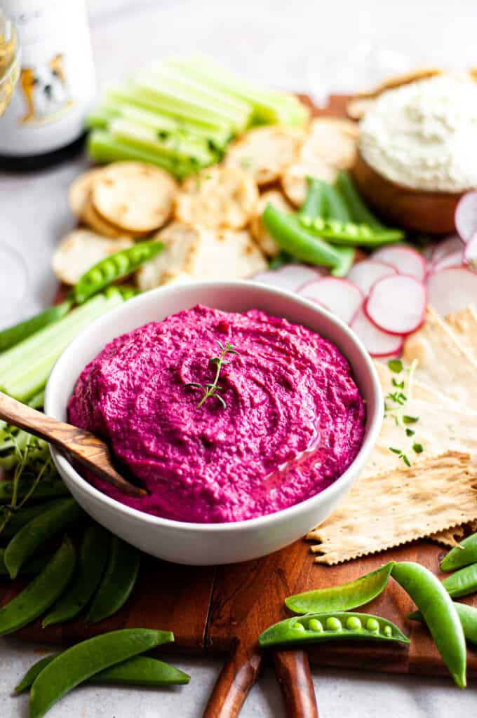 Beet hummus on board with vegetables and crackers