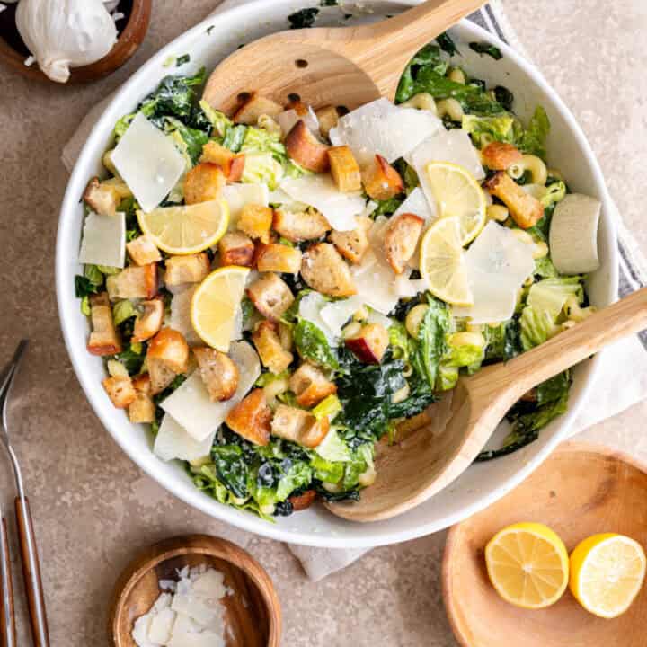 caesar pasta salad in a bowl topped with lemons