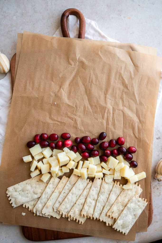 crackers, cheese, and cranberries on a board.