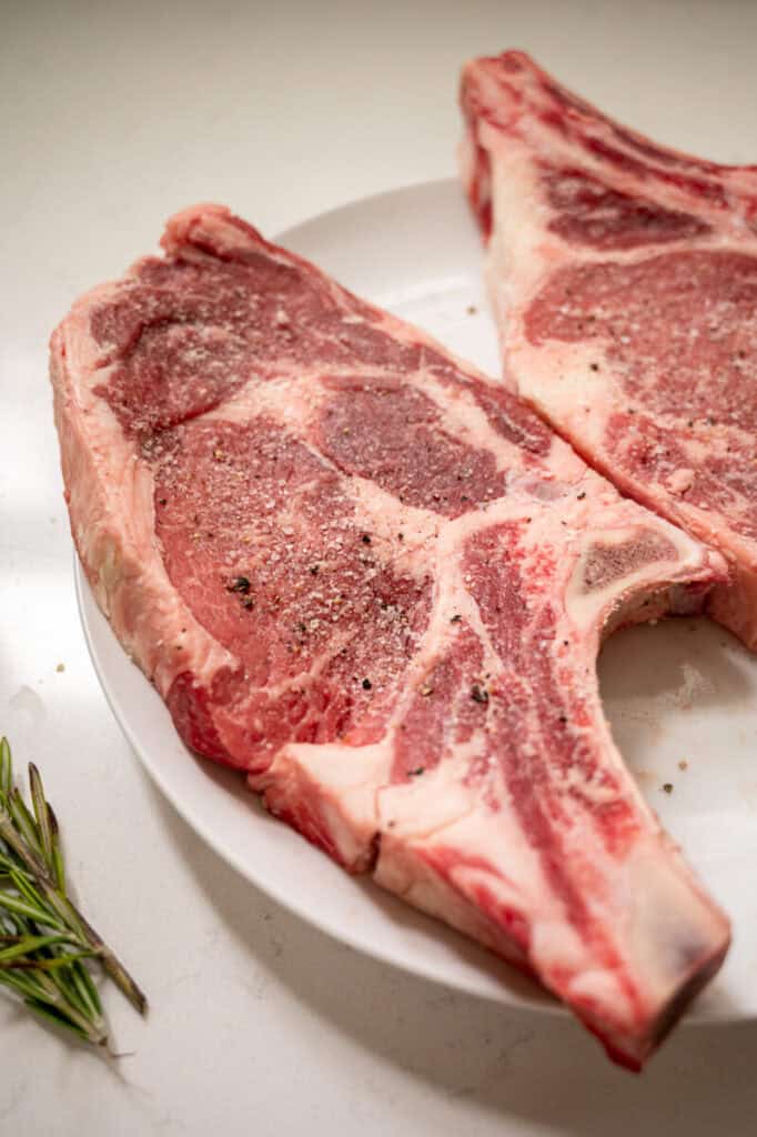 ribeye with salt and pepper on a plate.