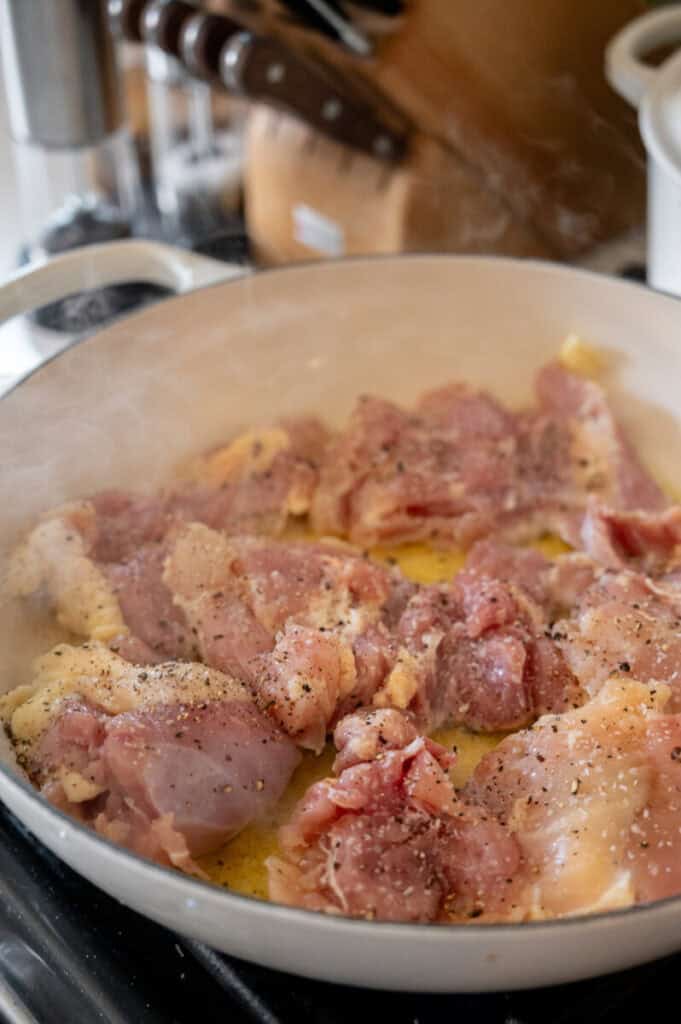 chicken thighs searing in a pan.