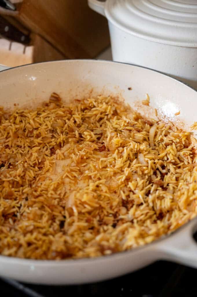 orzo sauteeing in a pan.