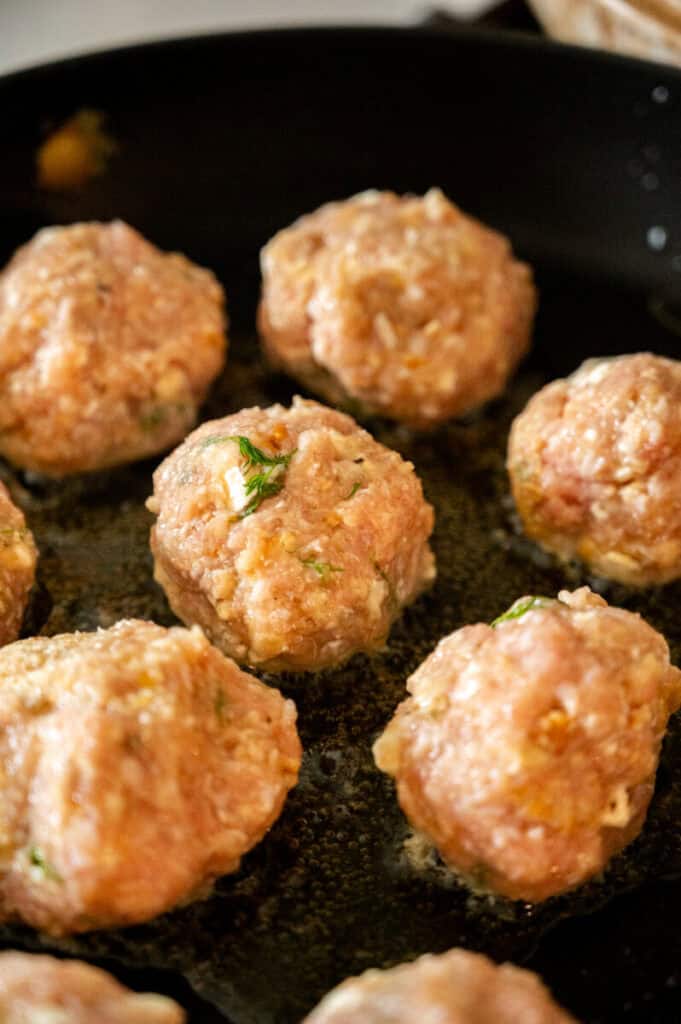 meatballs searing in a pan.