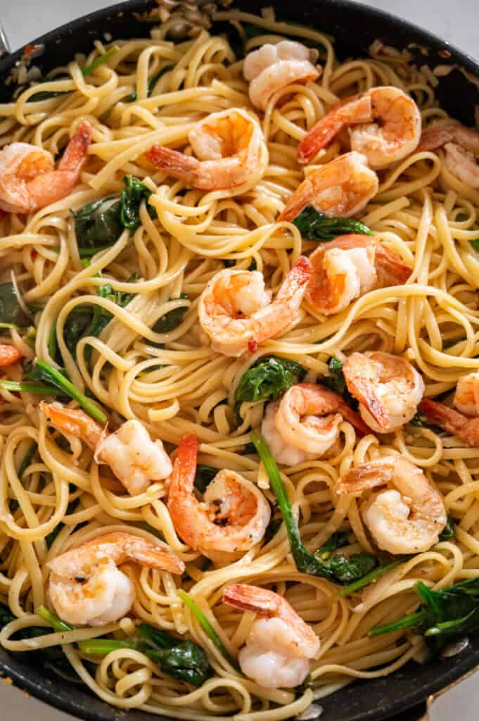 shrimp and spinach pasta in a skillet.